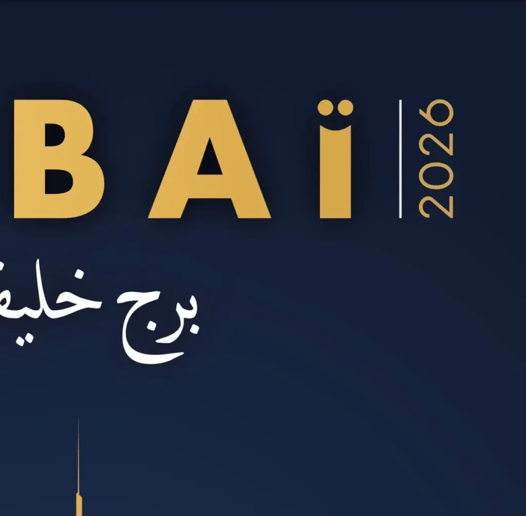 Gros plan détaillé du logo graphique pour la série 'Dubai 2026' sur fond bleu foncé, montrant le texte 'DUBAI' en or avec un 'I' en smiley stylisé, le texte vertical '2026' à droite, et du texte arabe blanc 'برج خليفة' (Burj Khalifa) ci-dessous.